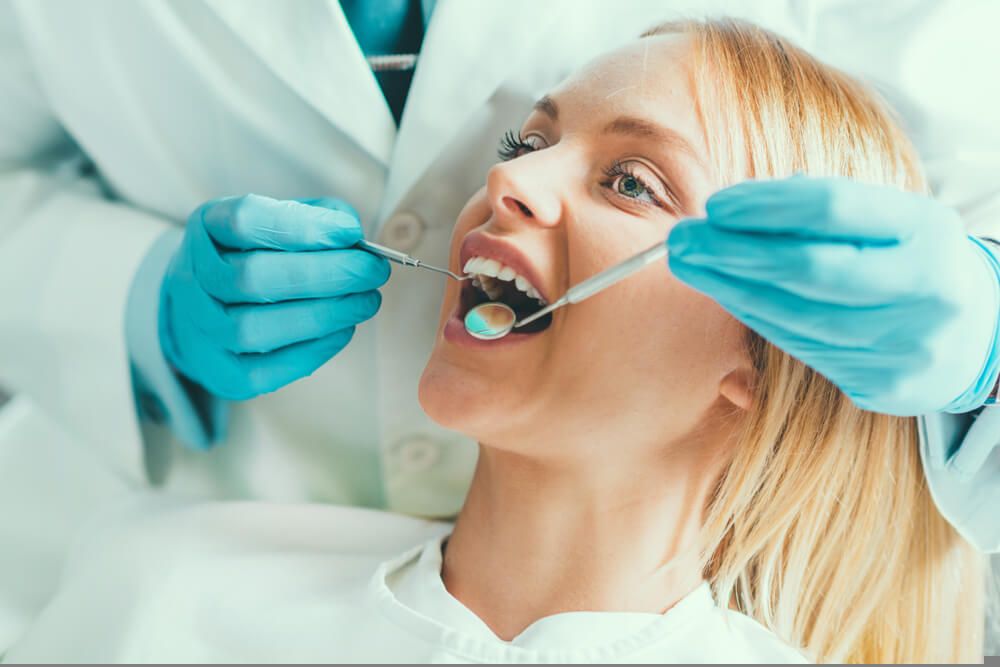 Woman with blonde hair having teeth examined by dentist
