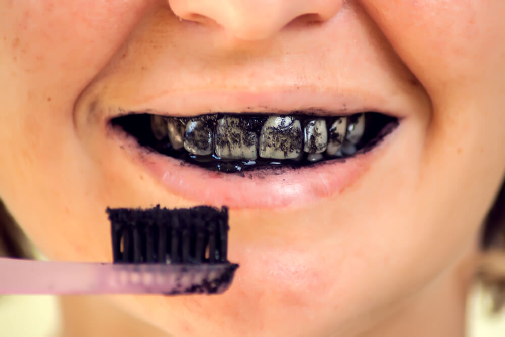 person brushing teeth with charcoal