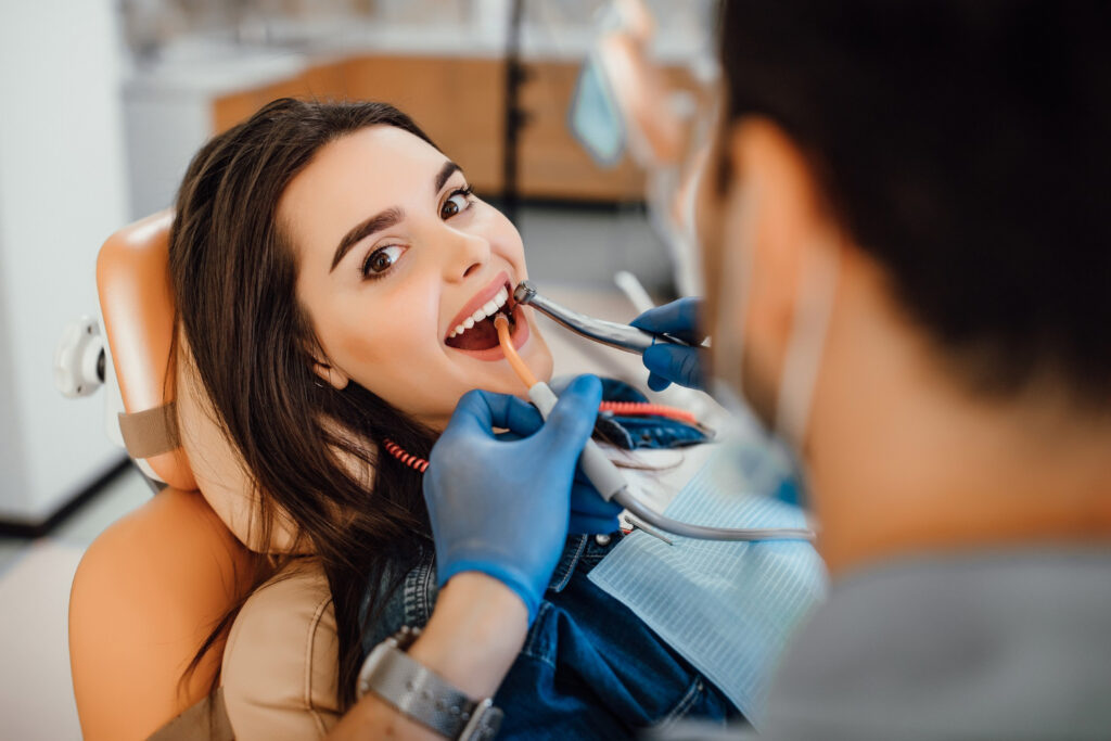 Woman receiving a professional teeth cleaning while sitting in a dental chair at Toothbar, emphasizing preventive dental care.