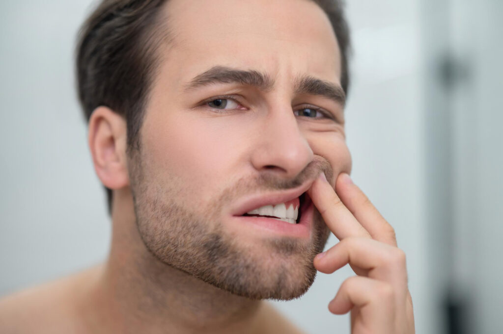 Man lifting his upper lip to reveal stained teeth, illustrating the need for cosmetic dental treatment