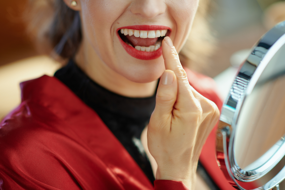 Woman pointing at her mouth, highlighting the durable results of her dental bonding treatment on a page discussing longevity