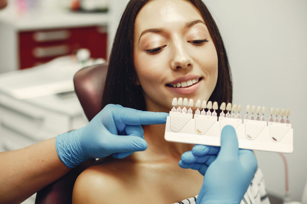 Dentist at Toothbar selecting the perfect shade of veneer on a female patient’s mouth, ensuring a natural and appealing smile