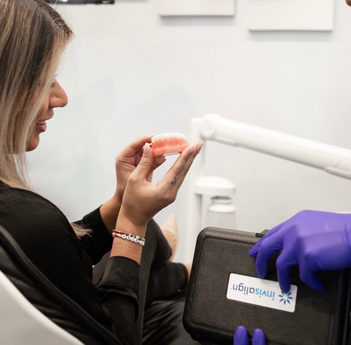 Female patient looking at model of teeth in hand.