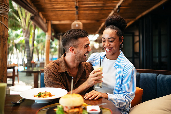 Couple smiling while enjoying meal at restaurant.