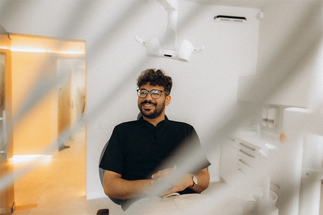 Patient with black glasses smiling in treatment chair.